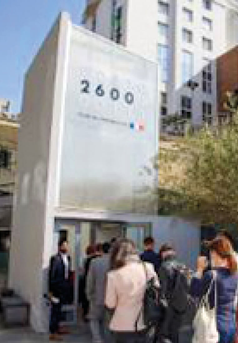 Photo de l’entrée de l’École 2600 avec des personnes qui attendent d’entrer