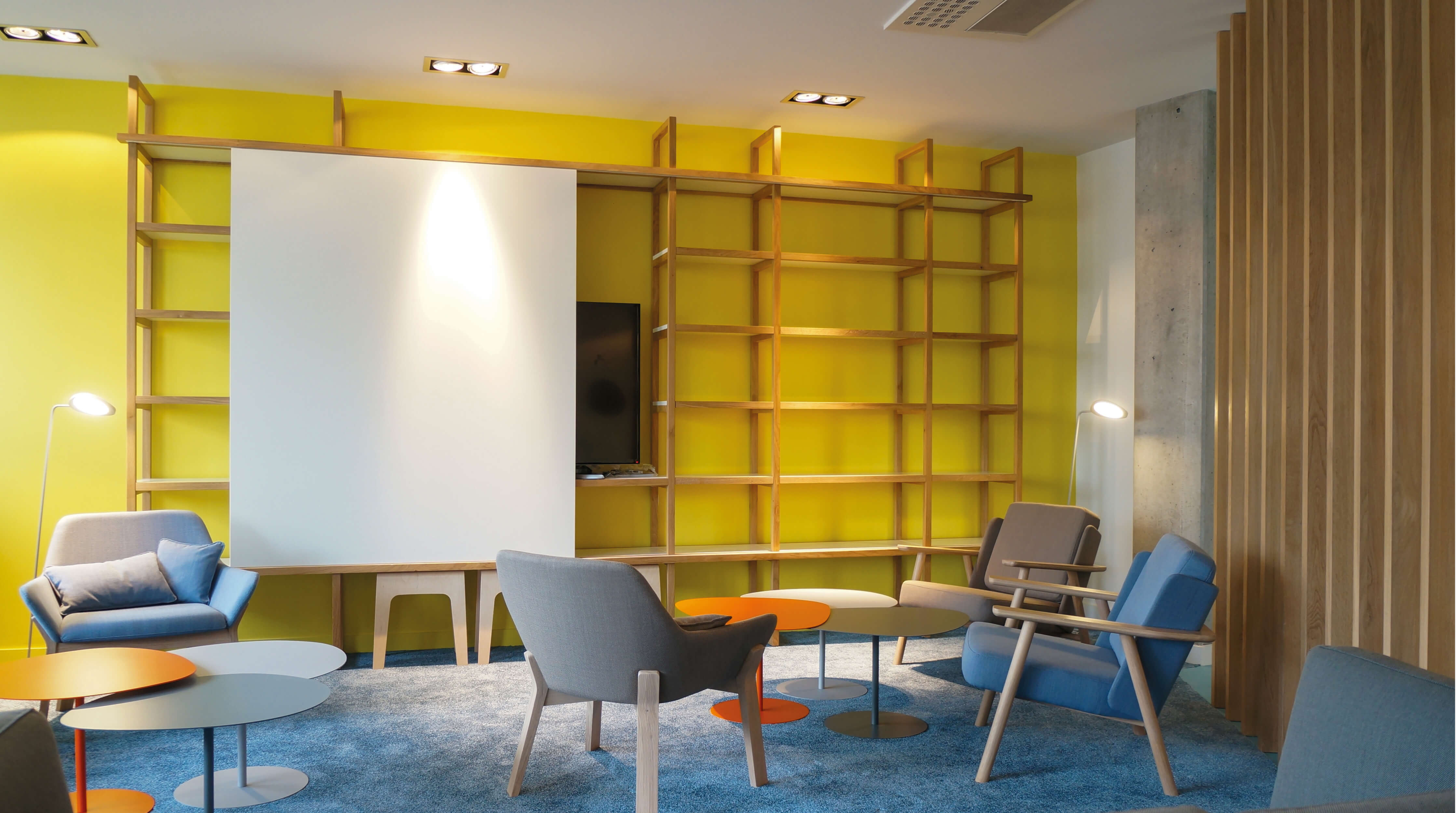 Photo de la bibliothèque modulable avec son panneau blanc entreouvert permettant de voir la télévision qu’il dissimule