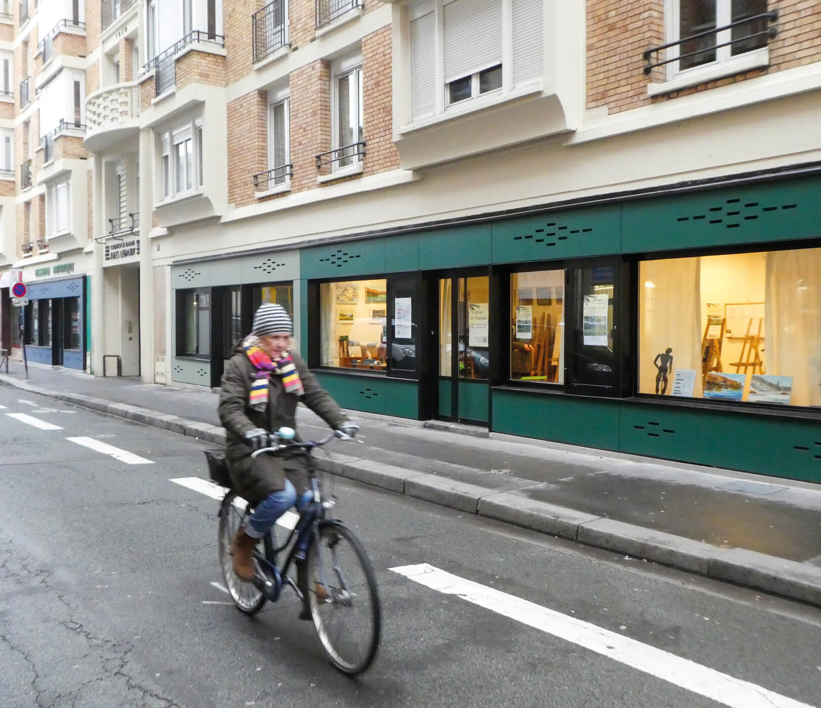 Photo d'une cycliste dans la rue avec les nouvelles devantures des locaux d'activites