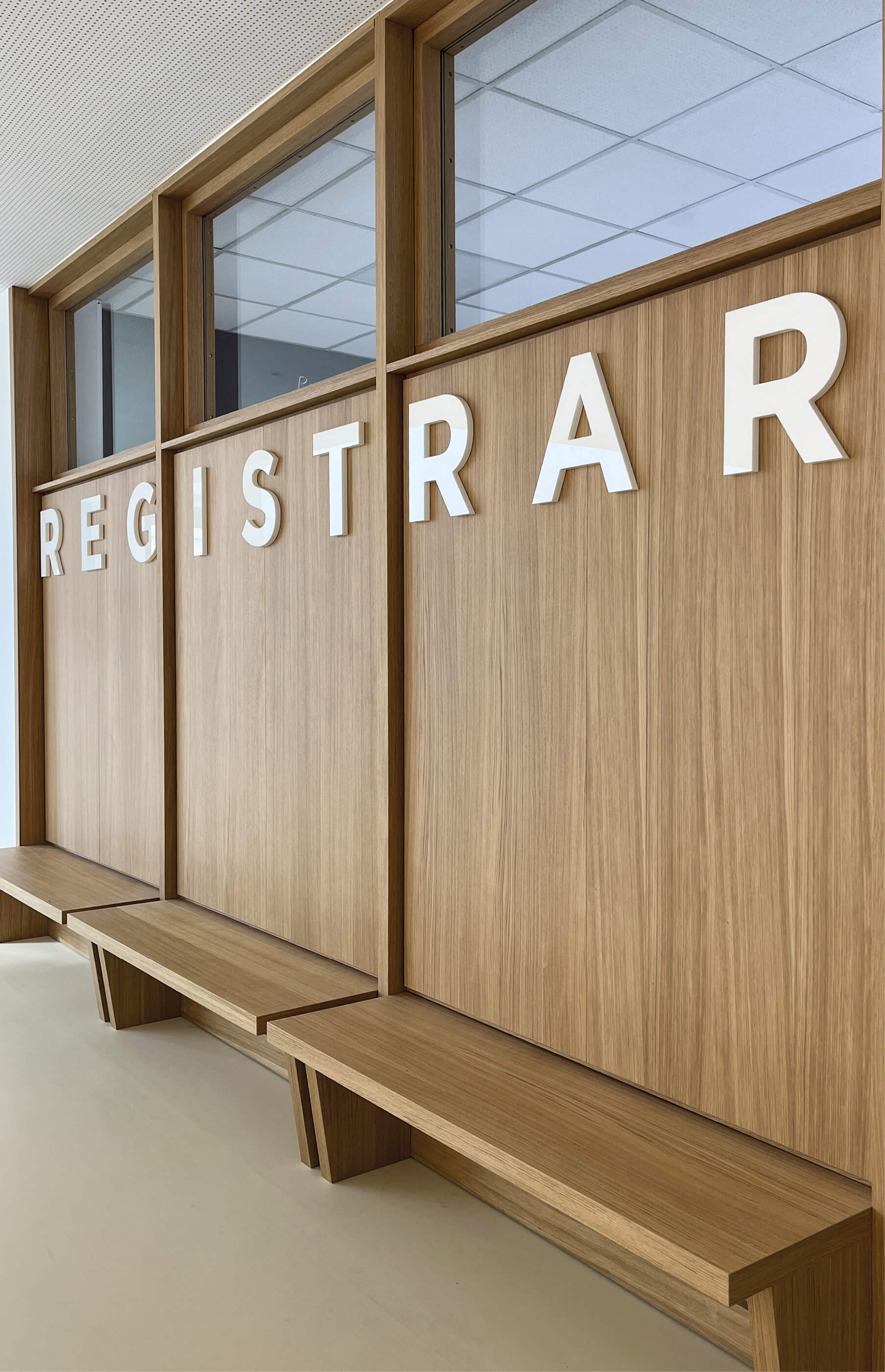 Photo des banquettes en bois lumineux adossées au bureau du Registaire de l'Essec après les travaux du grand hall dans le cadre du projet de restucturation du campus.