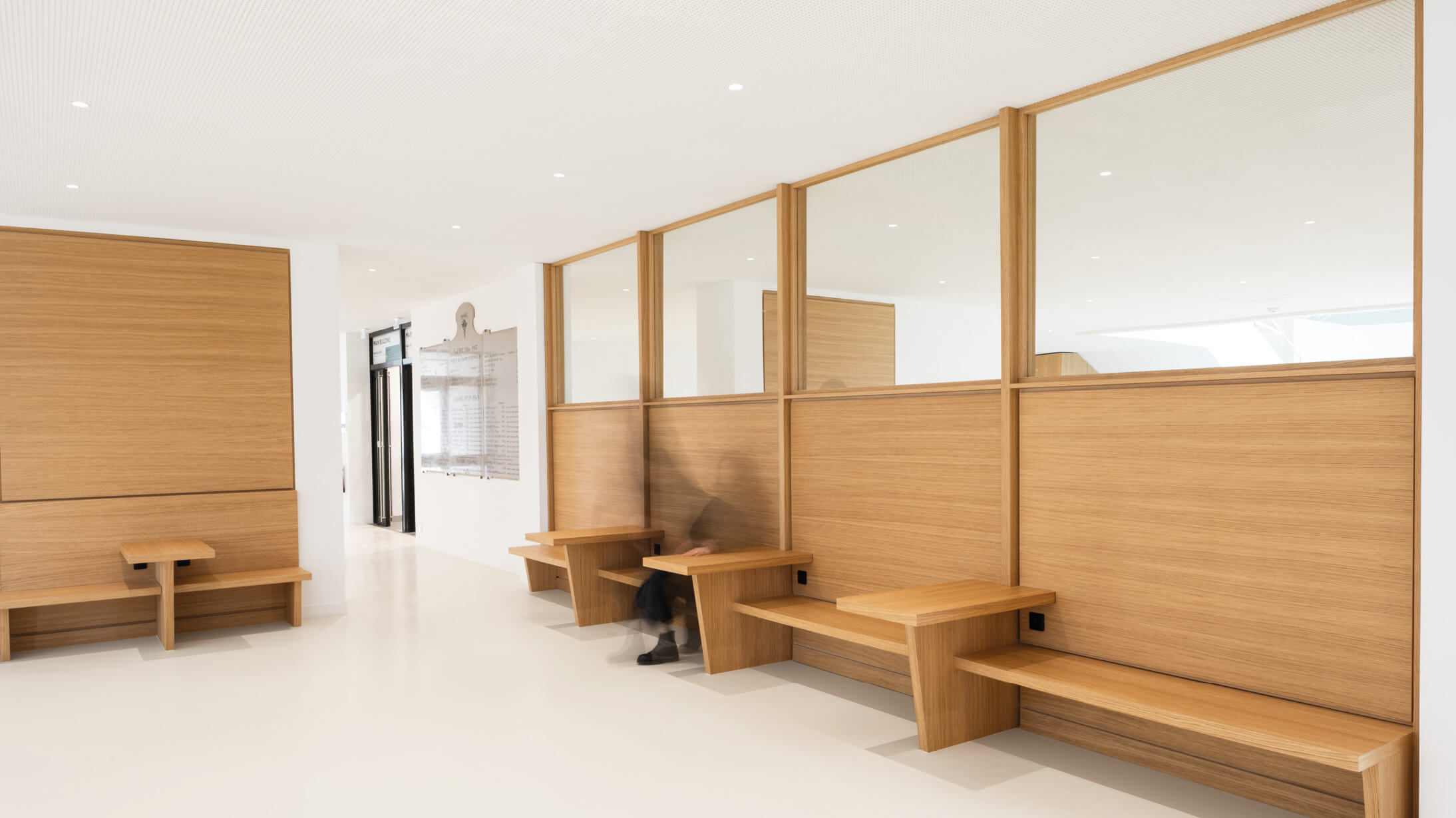 Photo des banquettes en bois installées dans le grand hall de l'Essec après restructuration du campus.