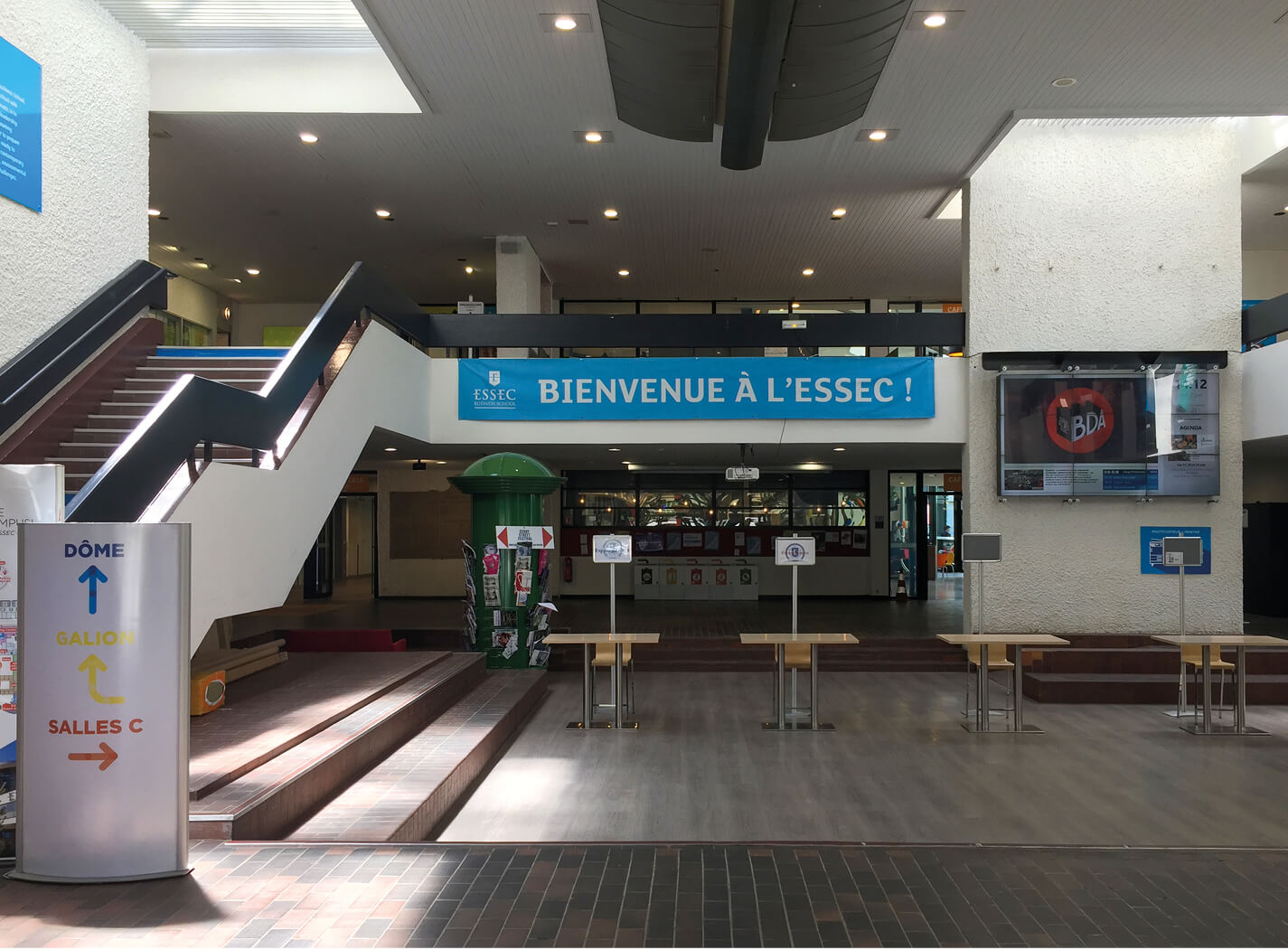 Photo du grand hall de l'Essec, son escalier, et le premier étage, un espace sombre avant le projet de restructuration campus.