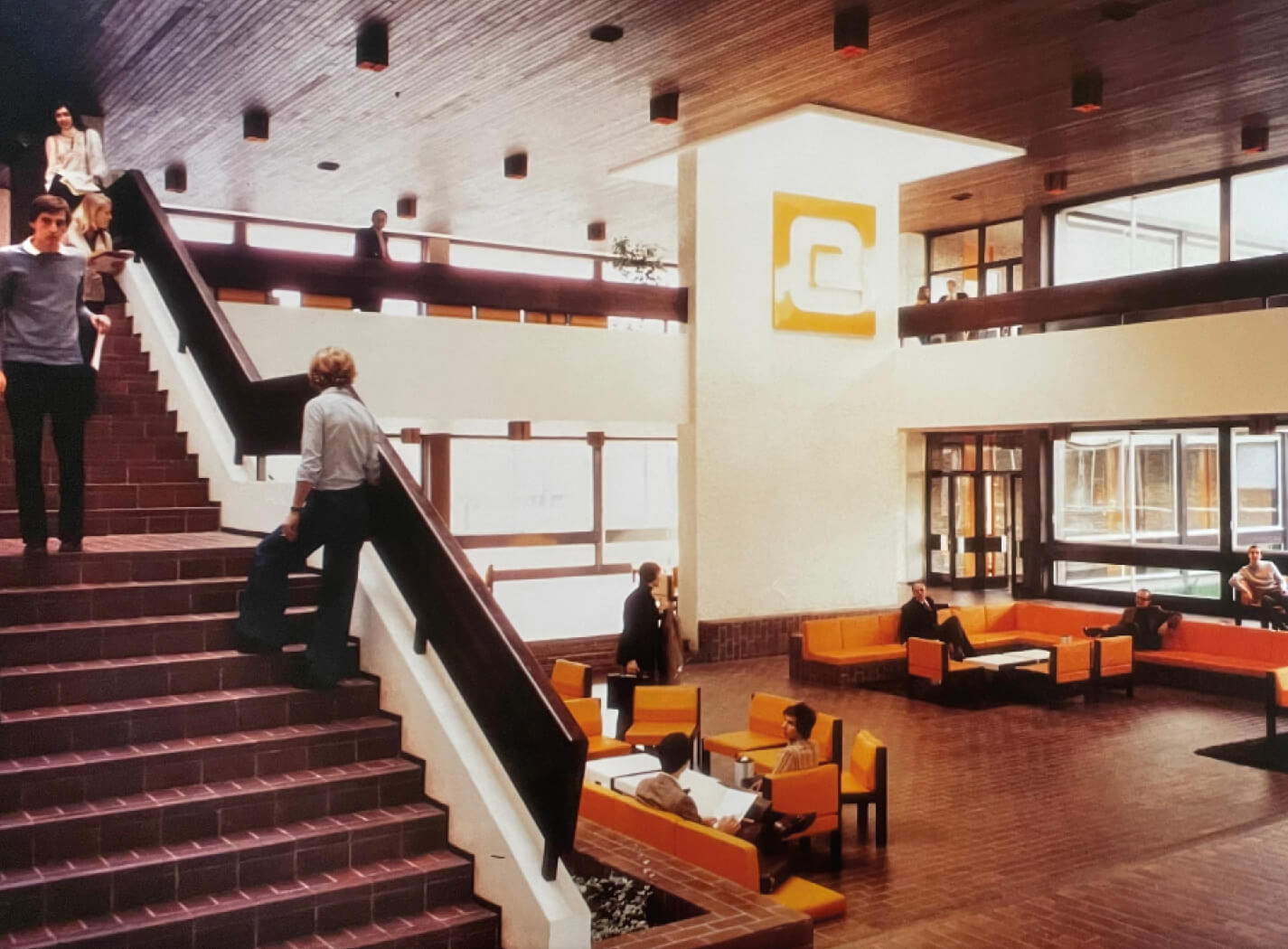 Photo d'archive du grand hall de l'Essec dont la décoration et le style vestimentaire des personnes laissent penser qu'elle a été prise dans les années 1970.