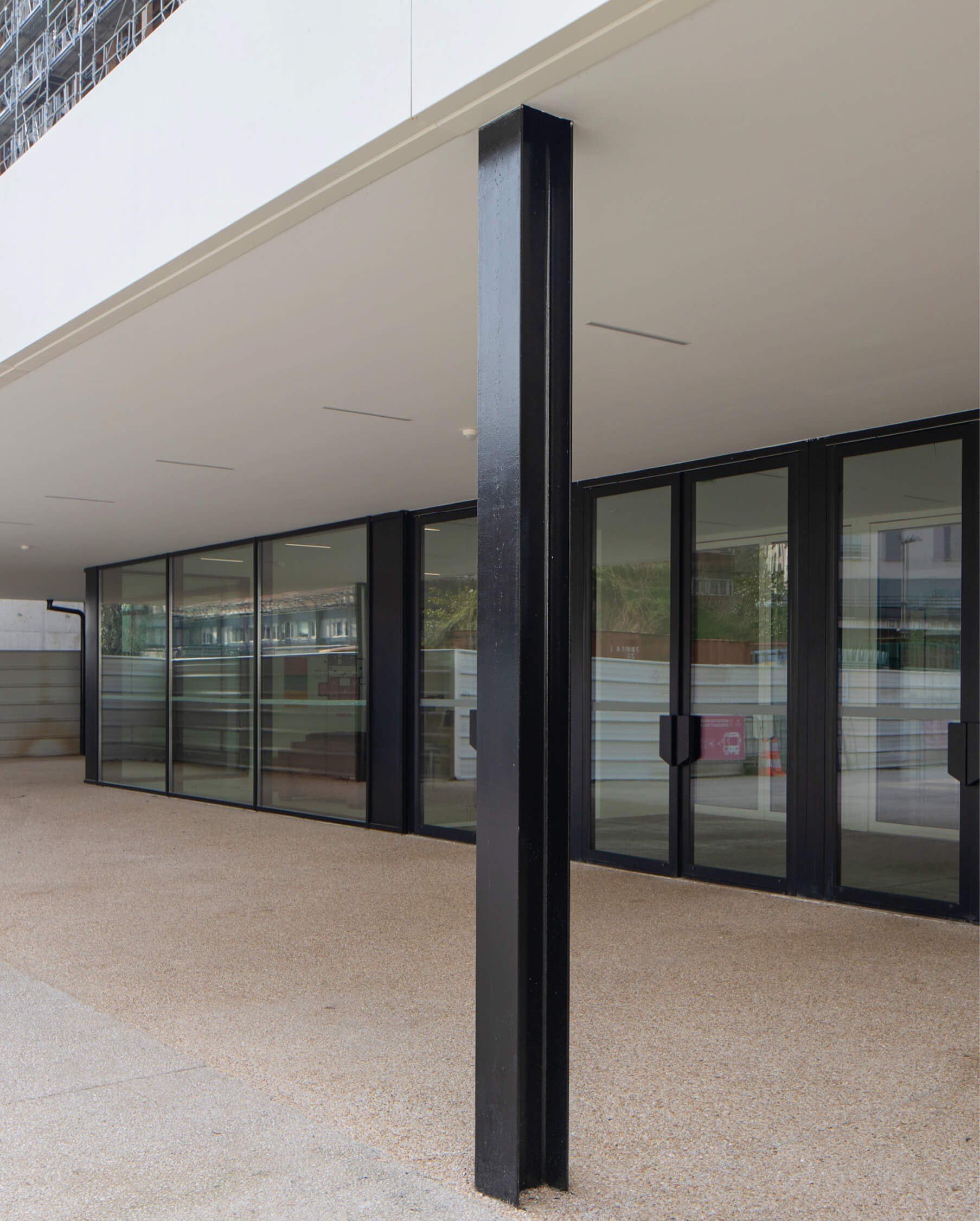 Photo d'un poteau du auvent de l'entrée de l'Essec avec les portes du grand hall en fond.