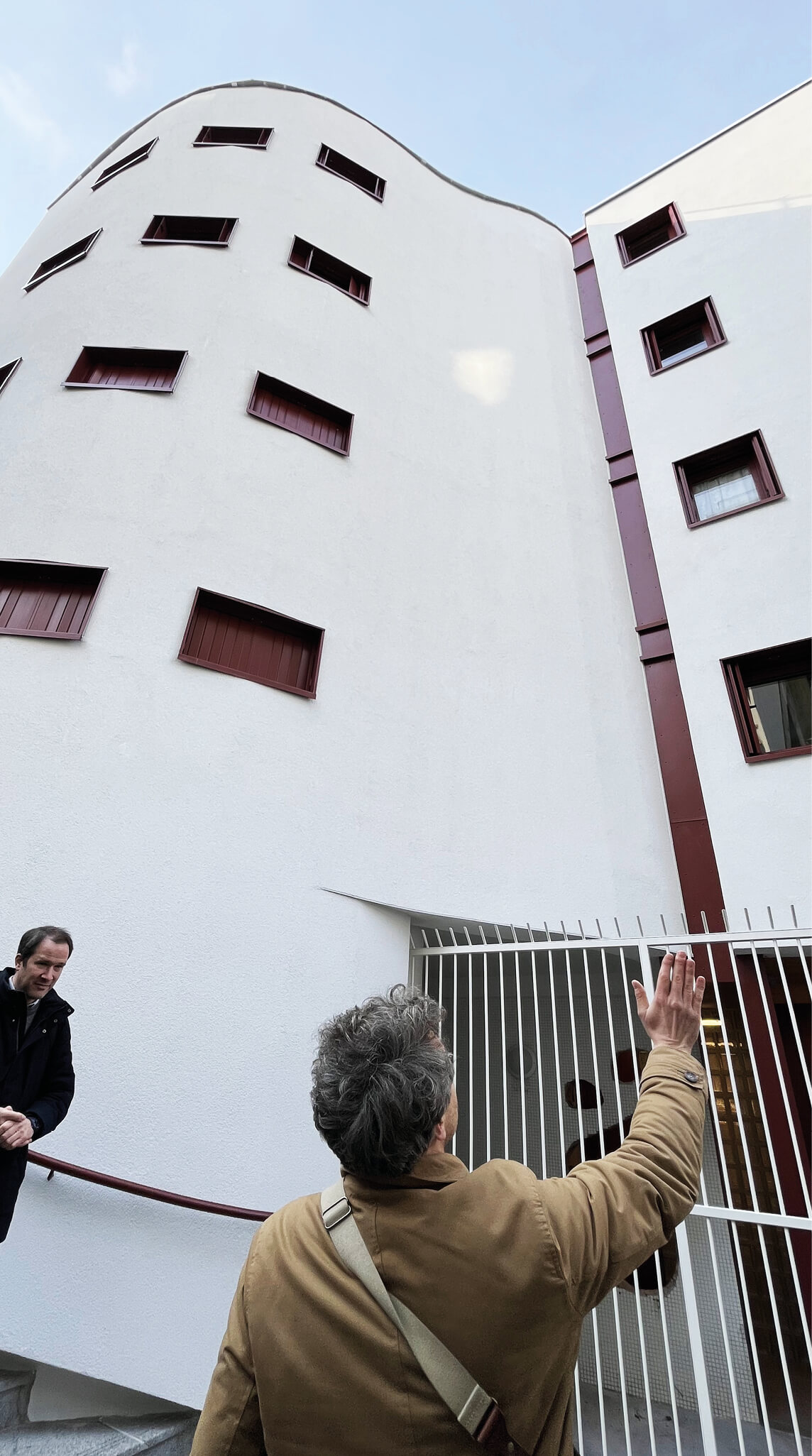 Photo en contreplongée de la façade d'un blanc éclatant avec détails rouges après la réhabilitation énergétique en milieu habité de l'immeuble-1.