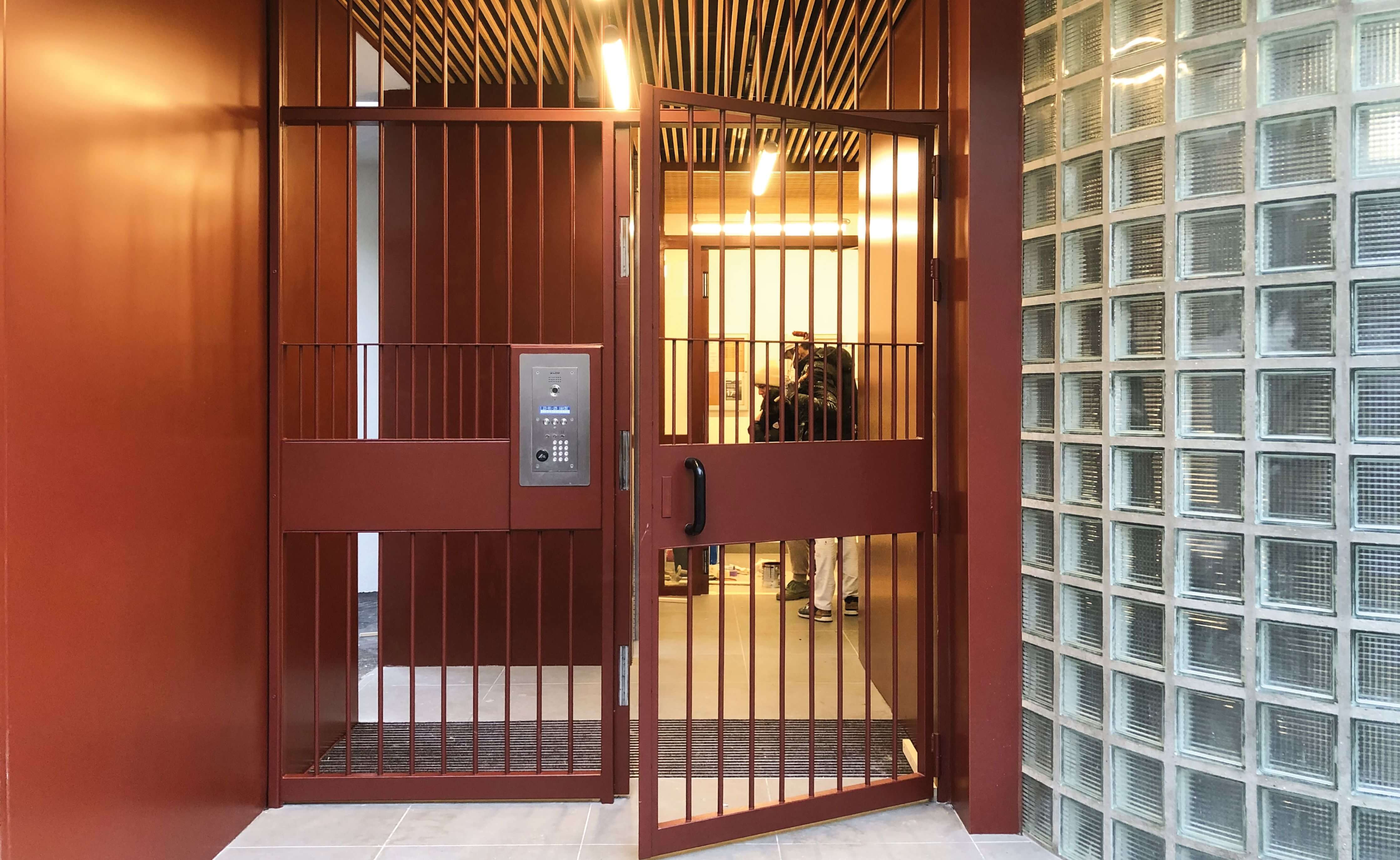 Photo de la grille d'entrée au rouge assorti à celui des façades la réhabilitation énergétique en milieu habité de l'immeuble de l'impasse Delépine.