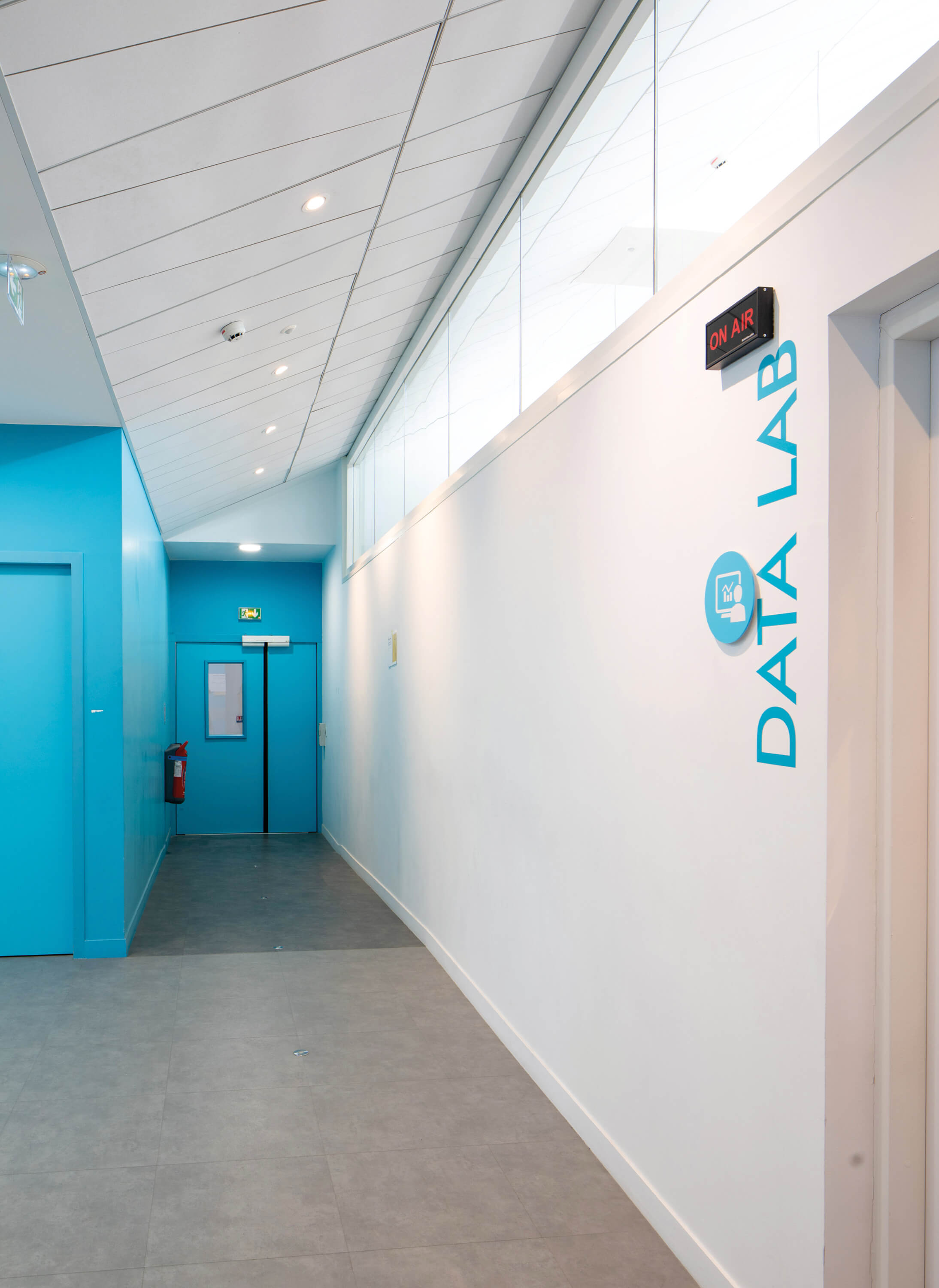 Couloir aux murs blancs et bleus devant le Data Lab du K-Lab de l’Essec.