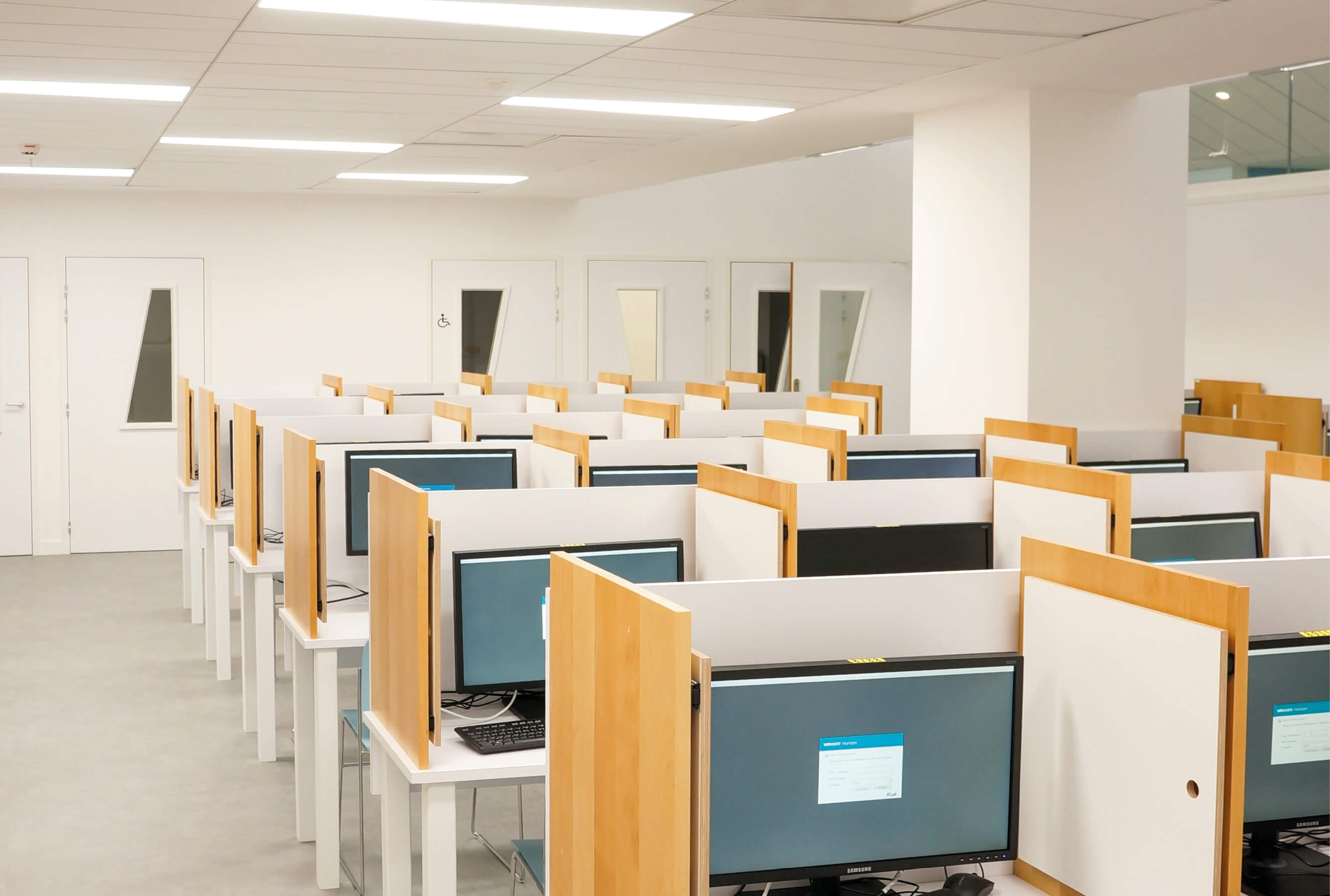 Photo de l’intérieur du Data Lab du K-Lab de l’Essec avec des rangées d’ordinateurs isolés les uns des autres.