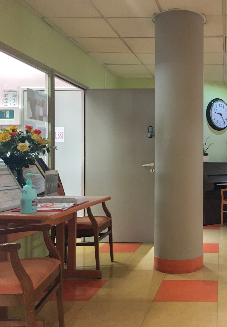 Photo montrant une des colonnes du hall de l’Ehpad La Citadine avec une table de travail, la porte du SSI avant le réaménagement des espaces communs