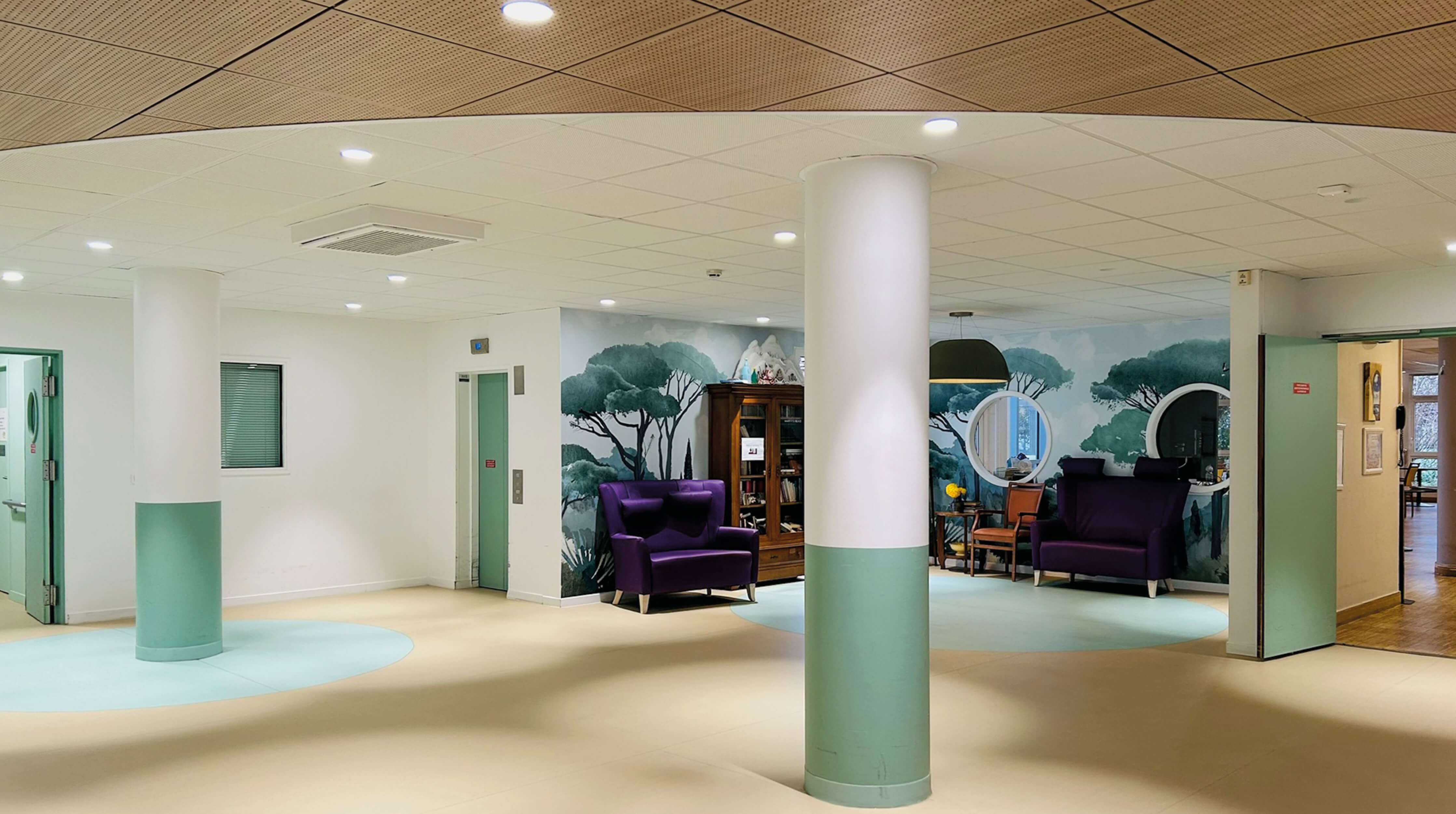 Photo de l’espace détente avec papier peint d’inspiration végétale, canapés en velours violet, armoire ancienne après le réaménagement des espaces communs de l’Ehpad La Citadine de Massy