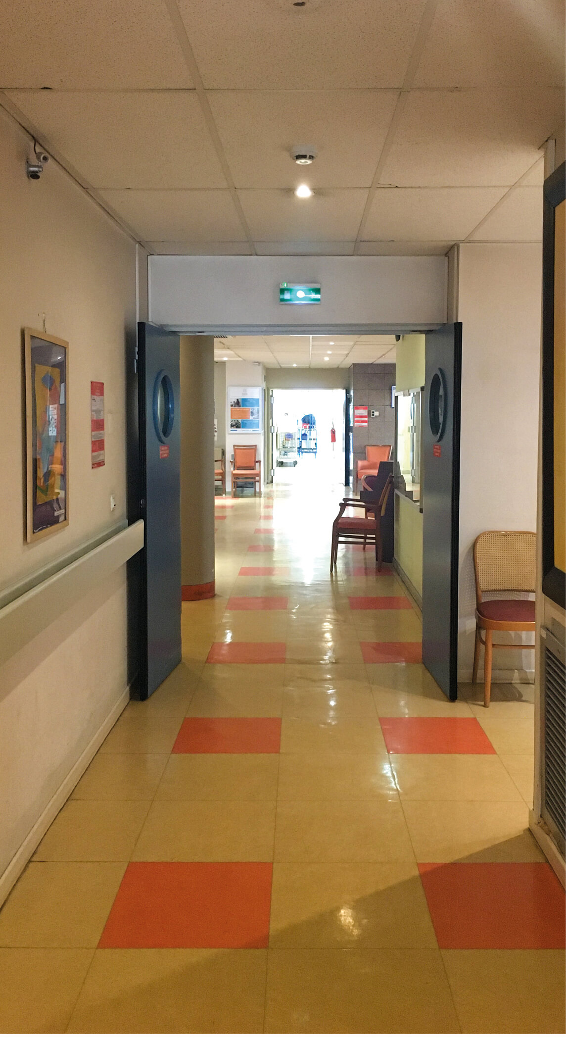 Photo d’un couloir avec carrelage beige et saumon, portes coupe-feu bleues avant le réaménagement des espaces communs de l’Ehpad La Citadine de Massy