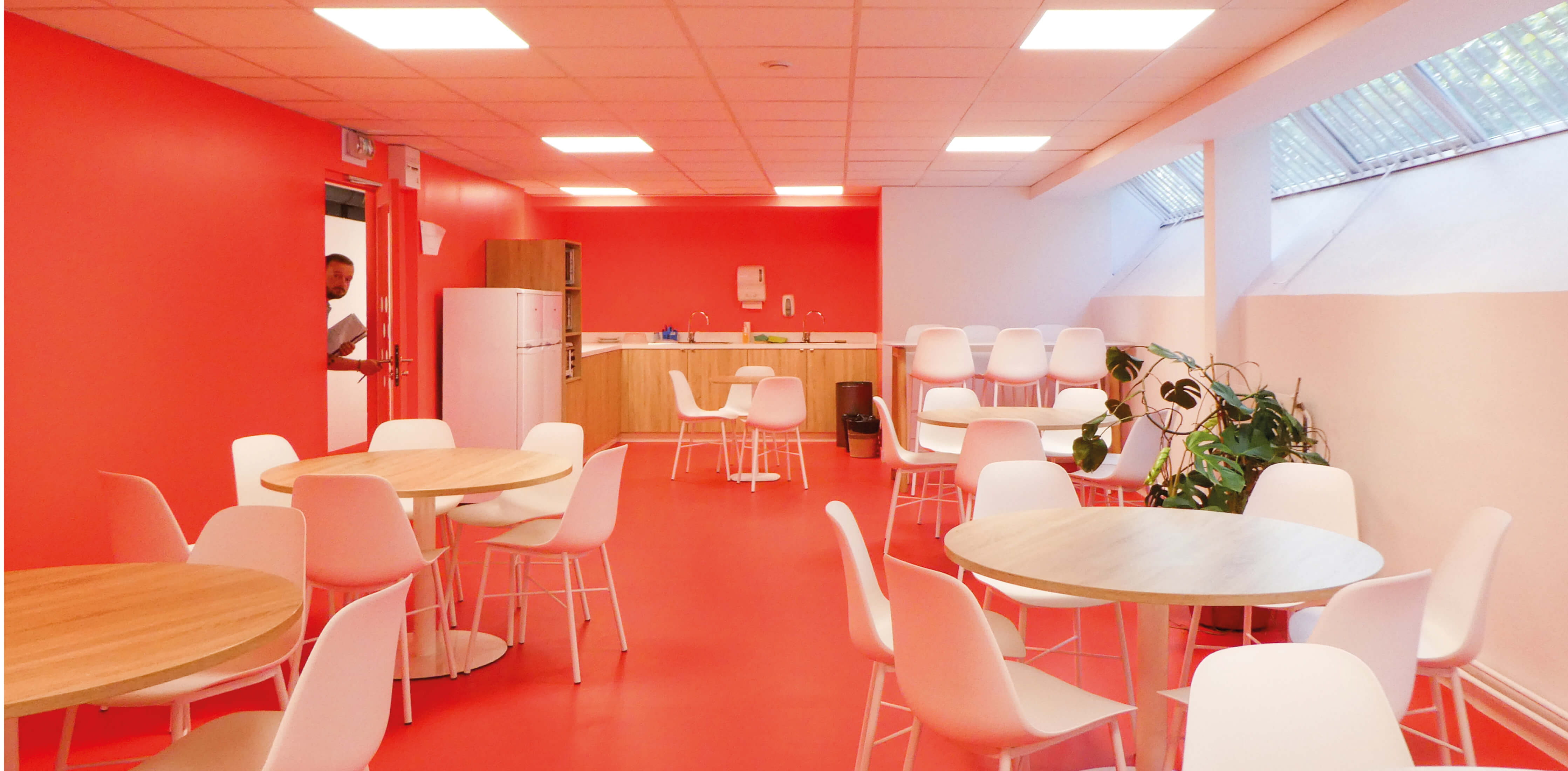 Photo de la cuisine aux murs rouges et mobilier bois et blanc après le réaménagement du siège de Val d’Oise Habitat La Palette.
