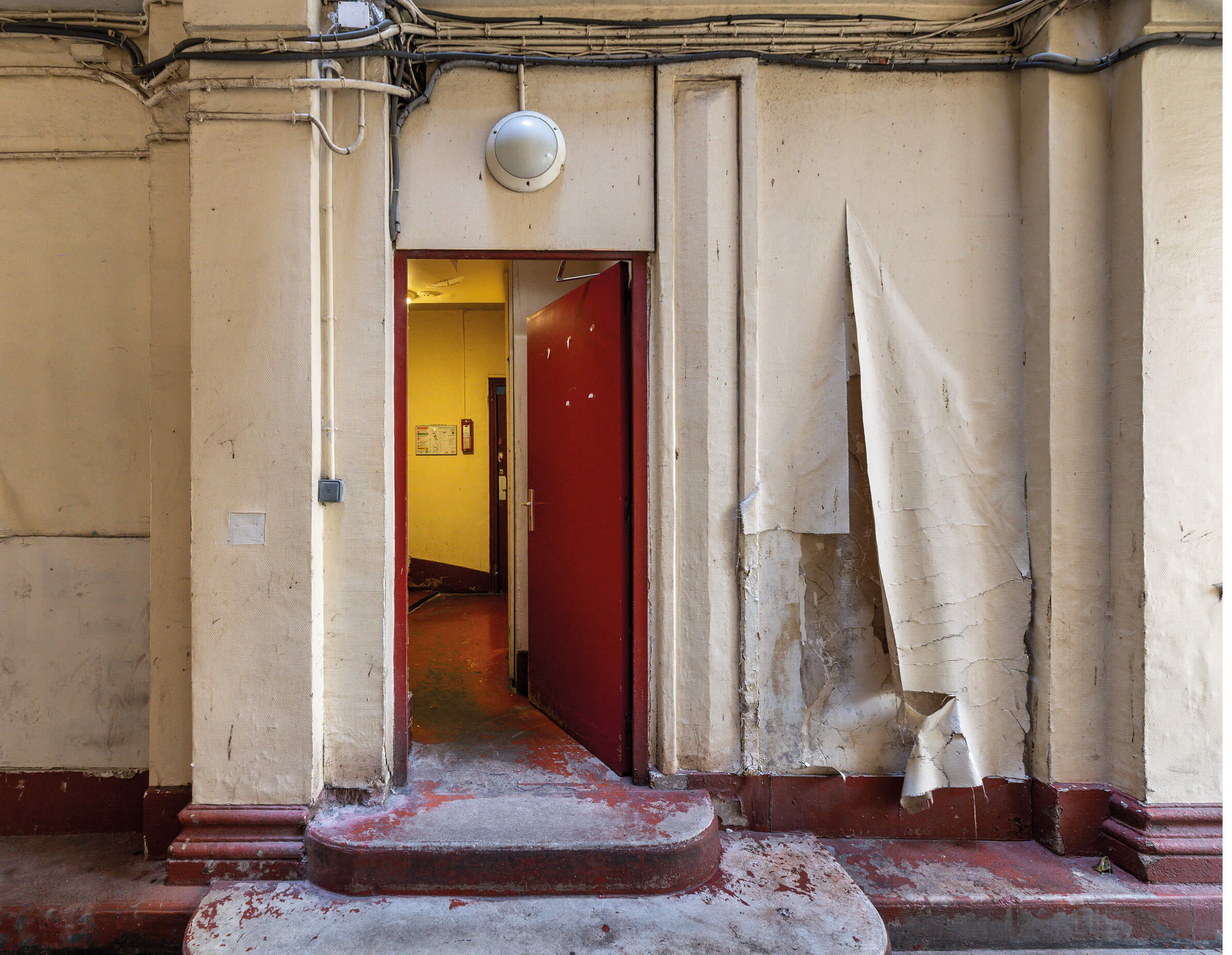 Photo d'une porte d'entrée délabrée de l'immeuble rue Caplat avant le projet de restructuration et réhabilitation rue Caplat