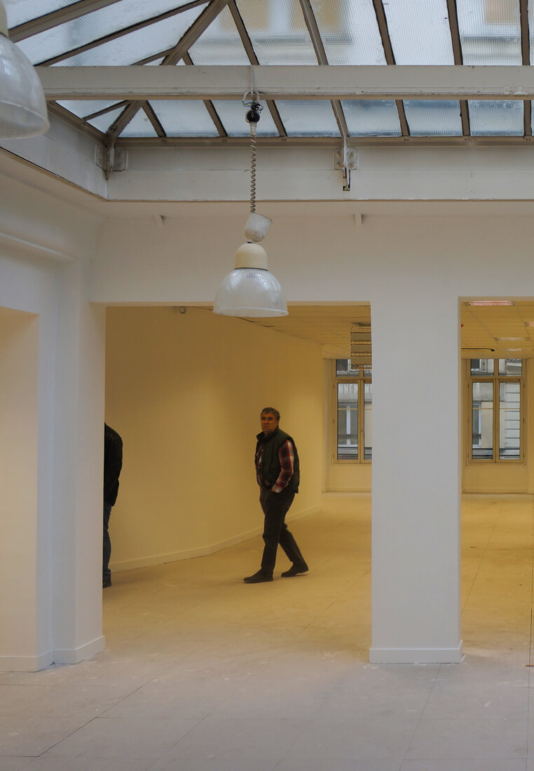 Photo de deux personnes visitant l’espace blanc avec verrière du Schoolab avant le projet d’aménagement