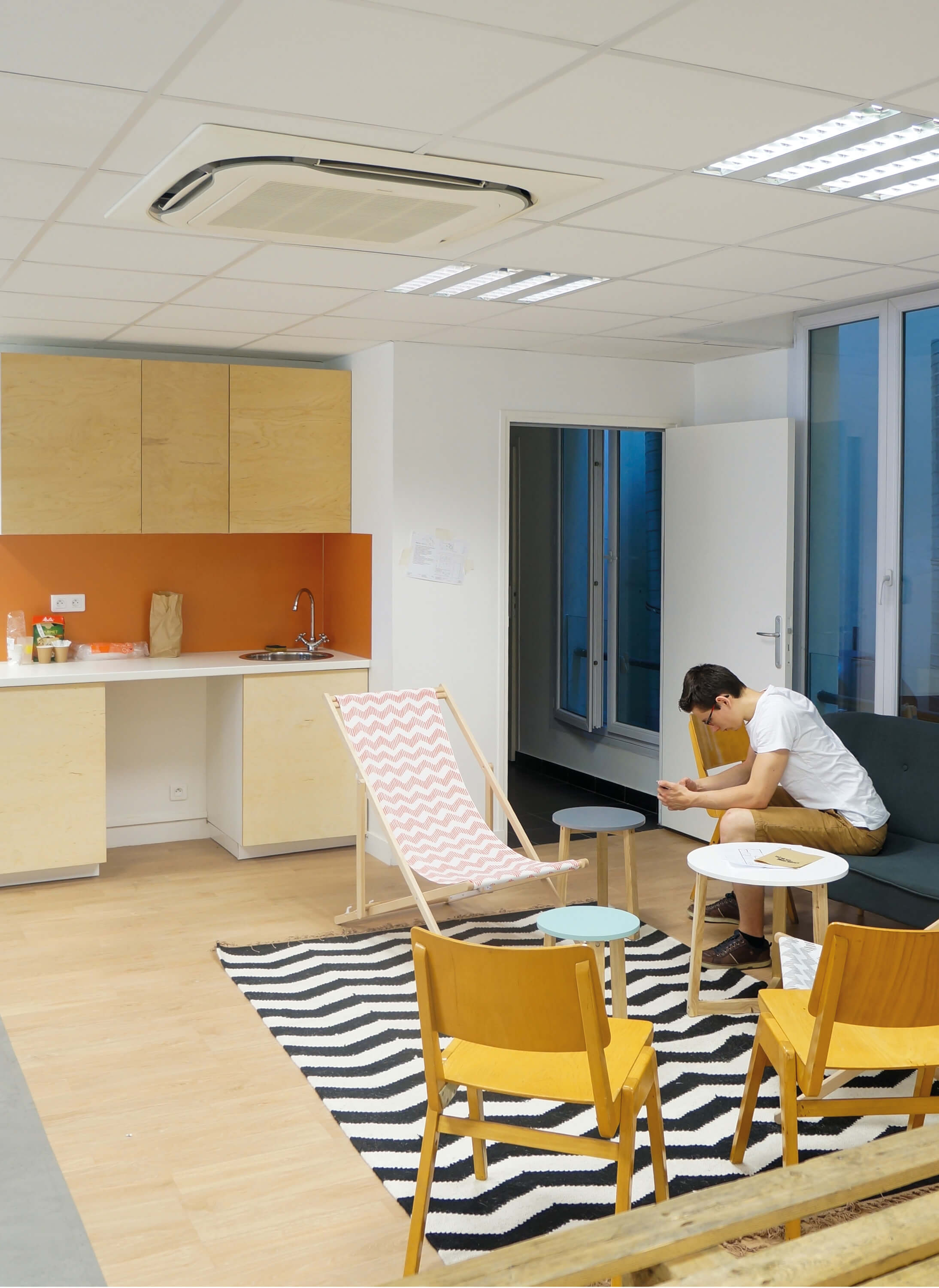 Photo d’un homme assis dans un espace détente coloré près d’un petit espace café.