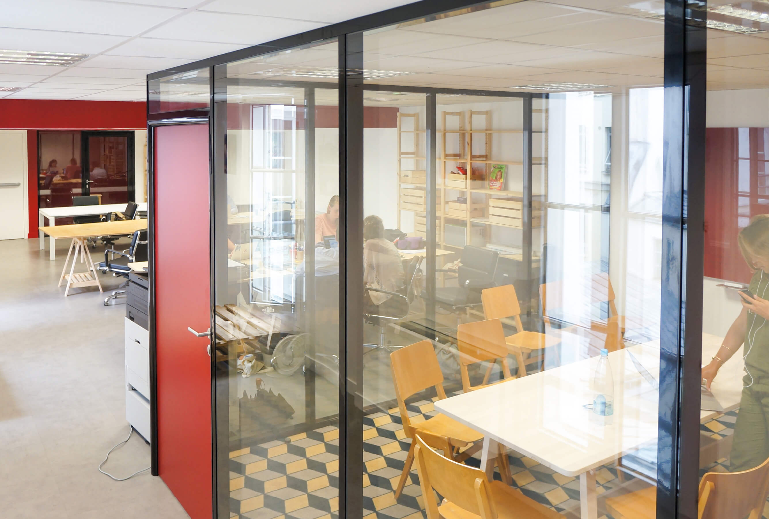 Photo d’un open space aux détails déco rouge avec salle de réunion vitrée.