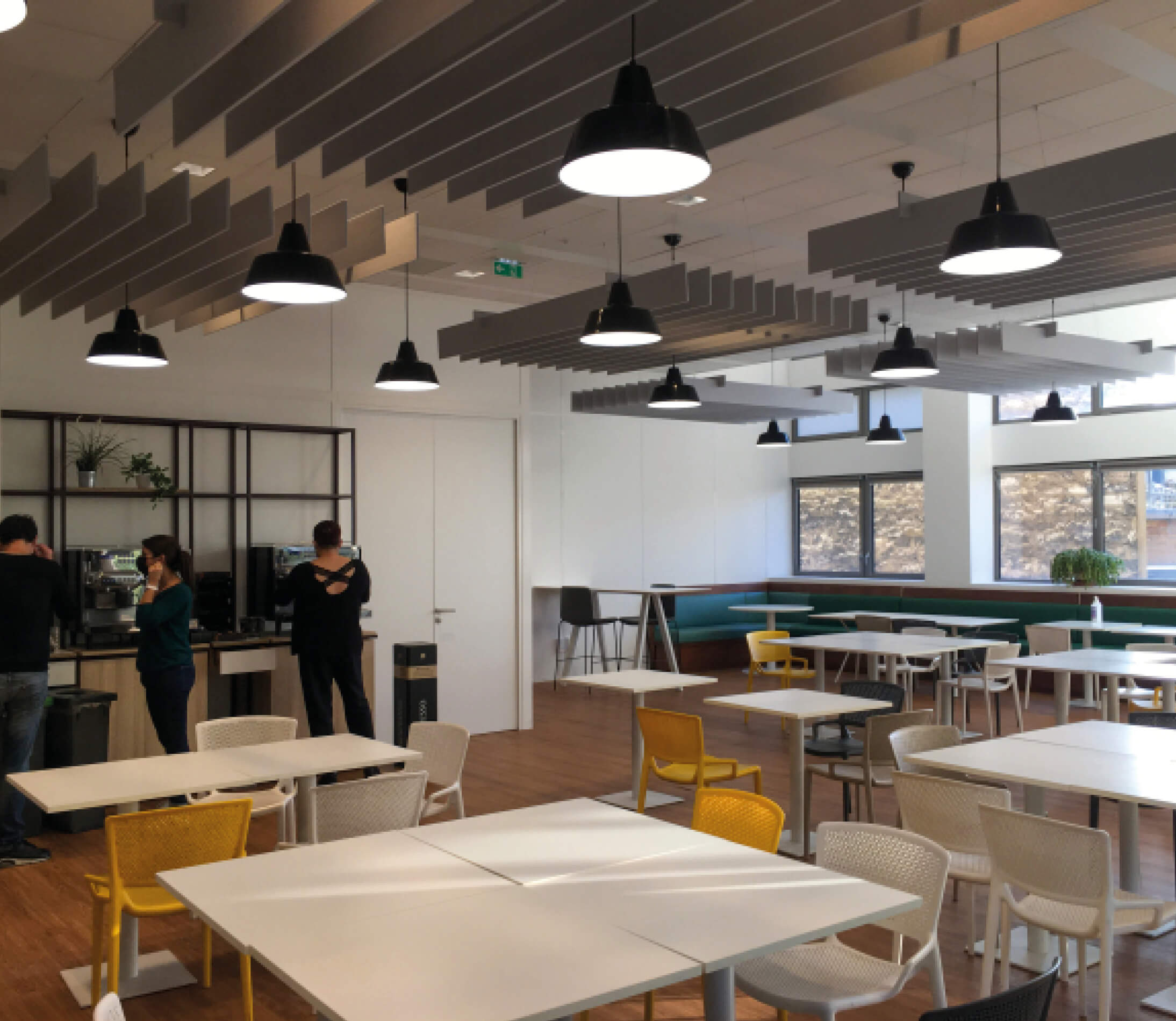 Photo de personnes aux machines à café de la salle déjeuner après réaménagement du siège social de la société Iqera