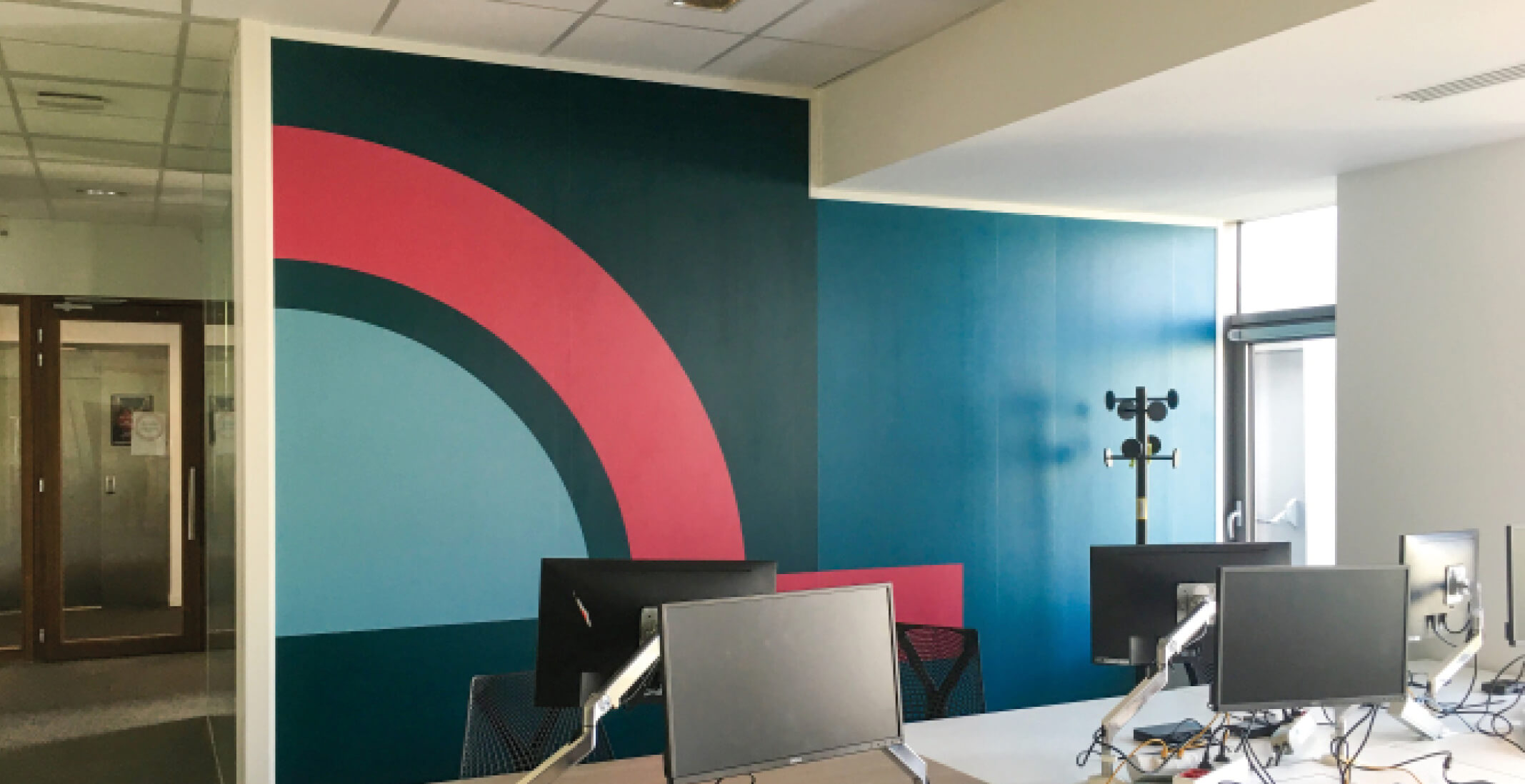 Photo de bureaux avec fresque colorée en arrière-plan après le réaménagement du siège social de la société Iqera