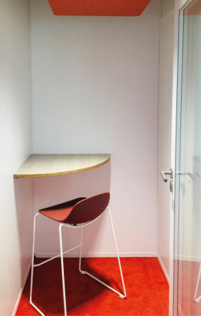 Photo de l’intérieur d’une cabine acoustique avec table d’angle et chaise haute après le réaménagement du siège social de la société Iqera
