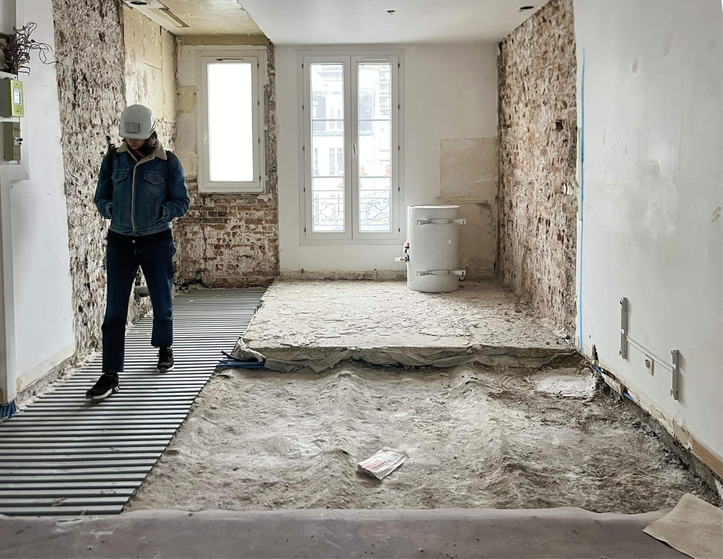 Photo du chantier restructuration et réhabilitation plan climat rue Émile Lepeu montrant l’ouverture qui accueillera une nouvelle fenêtre avec deux ouvriers en arrière-plan