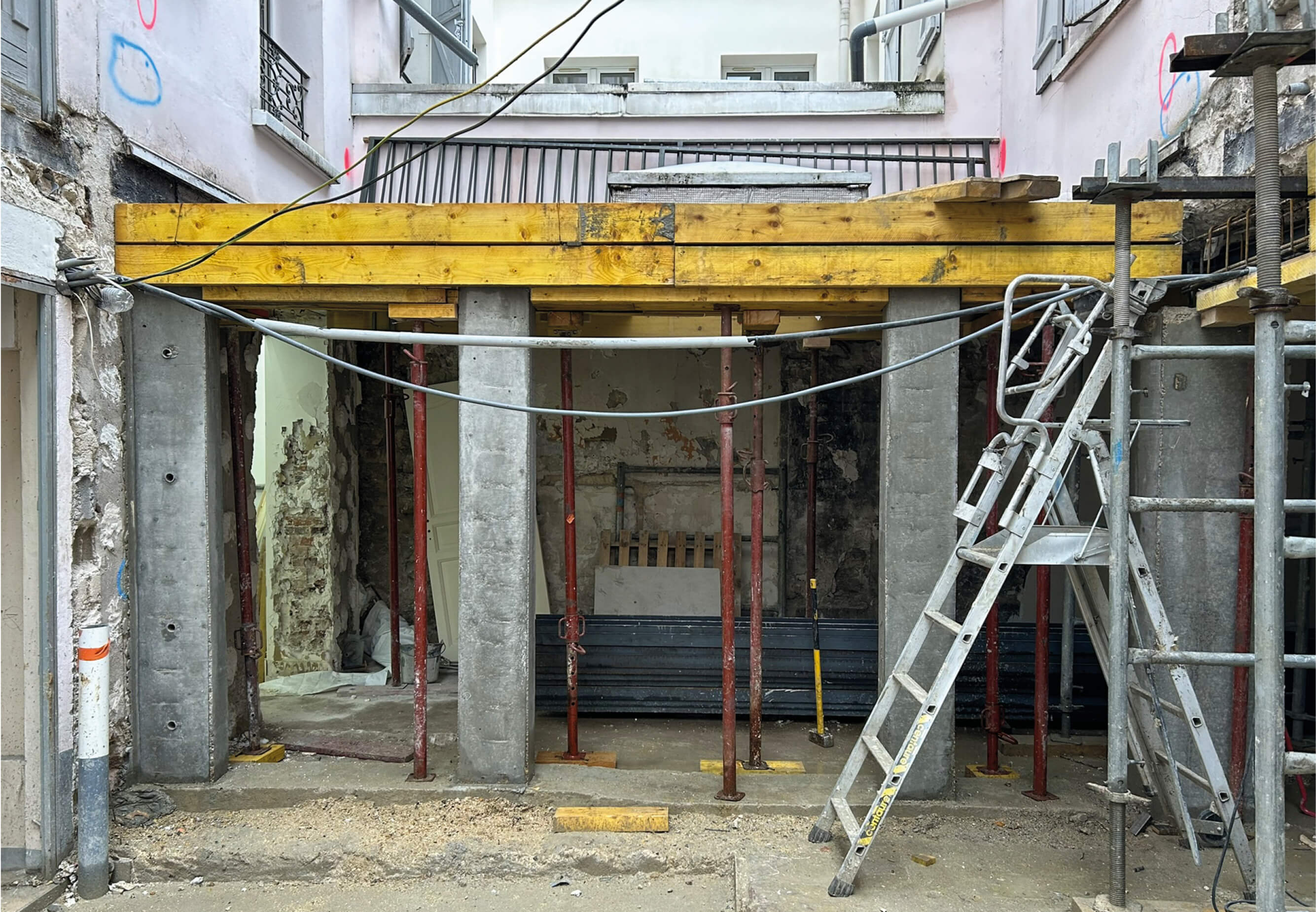 Photo du chantier restructuration et réhabilitation plan climat rue Émile Lepeu montrant des piliers de bétons surmontés de poutres en bois