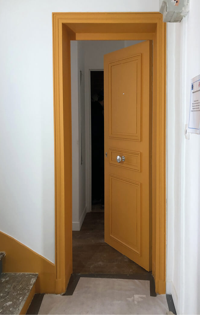 Porte d’entrée entrouverte d’un appartement du projet réhabilitation et réhabilitation plan climat rue Émile Lepeu