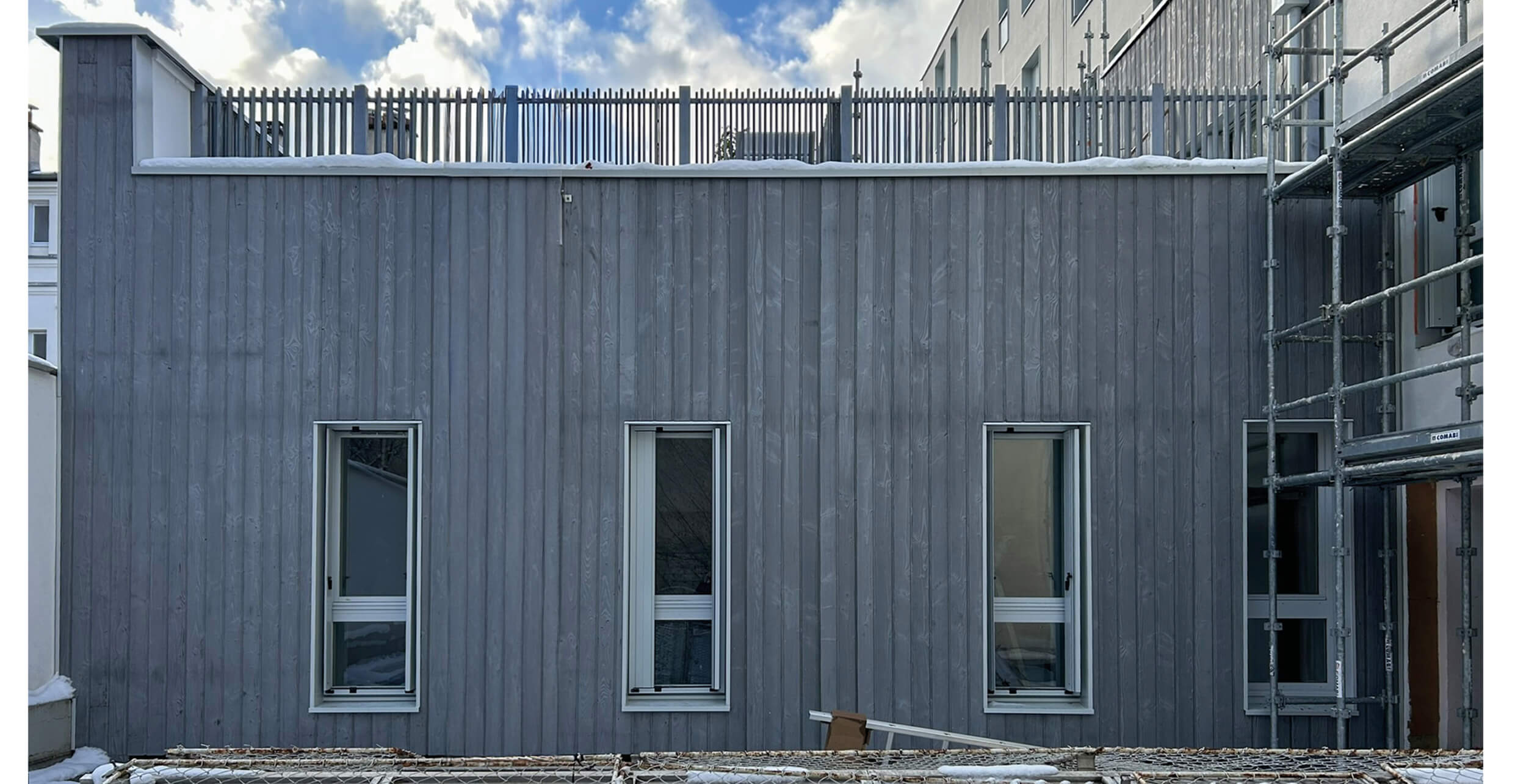 Photo d’un ouvrier travaillant à la finalisation de la façade sur l’échafaudage d’un immeuble rue Émile Lepeu du projet réhabilitation et réhabilitation plan climat