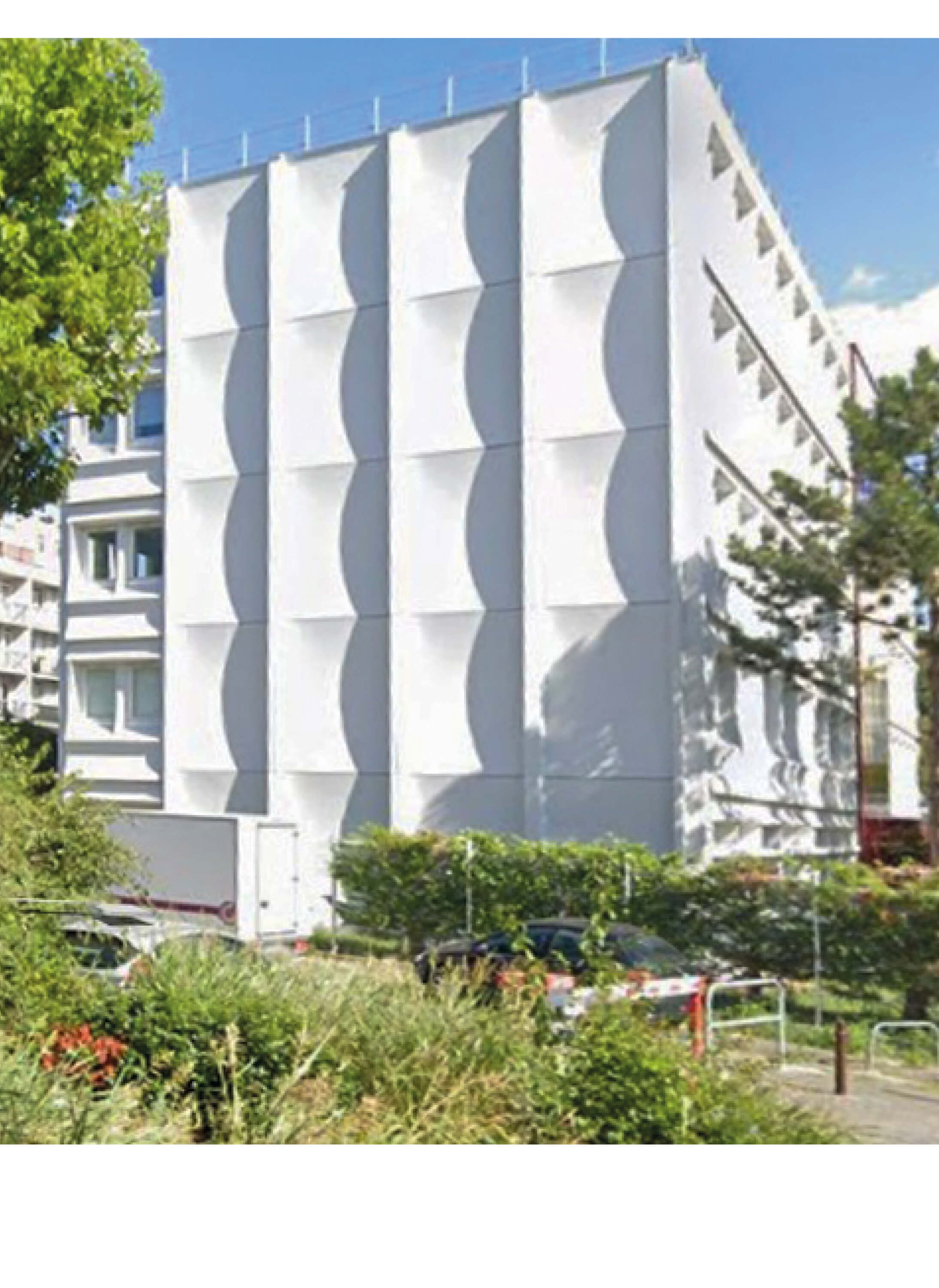Photo immeuble blanc du site du projet d’extension et d’aménagement du siège d’Est Ensemble Habitat avec la végétation verdoyante