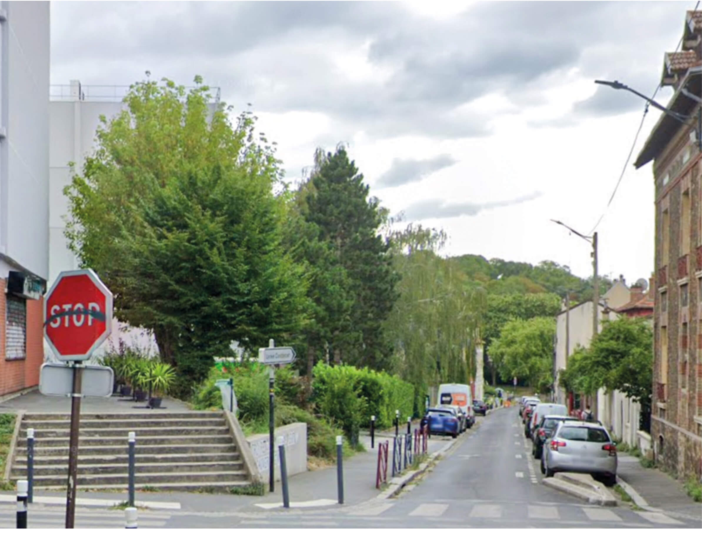 Photo d’une rue bordée de pavillons, d’arbres verdoyants et d’immeubles sur le site du projet d’extension et d’aménagement du siège d’Est Ensemble Habitat