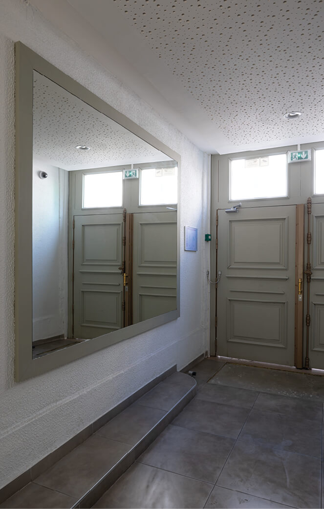 Photo du hall d’entrée avec grand miroir et porte de sortie dans le cadre du projet de réhabilitation plan climat en milieu habité rue Jeanne d’Arc