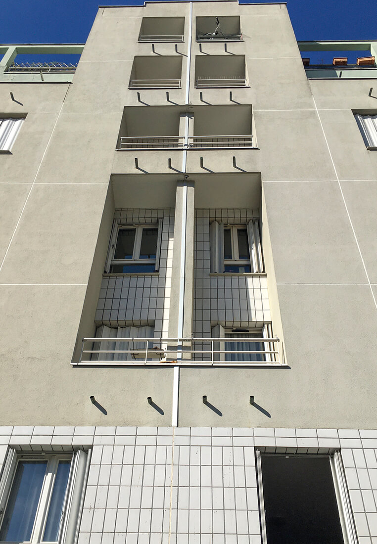 Photo en contre-plongée des fenêtres et loggias du bâtiment concerné par le concours pour la rehabilitation plan climat rue kergomard avec ciel bleu