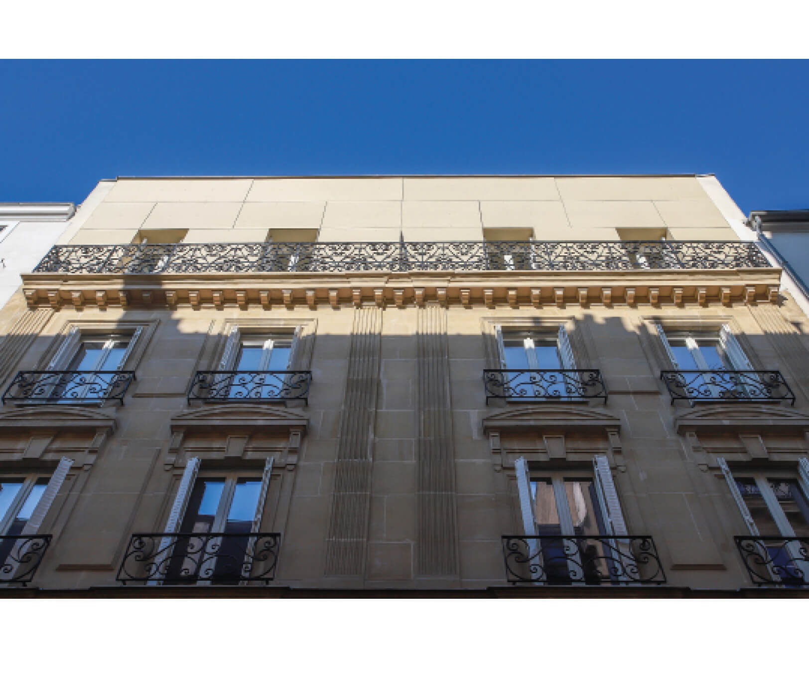 Photo en contre-plongée des étages supérieurs de la façade rue Sauffroy avec un ciel bleu après restructuration et réhabilitation