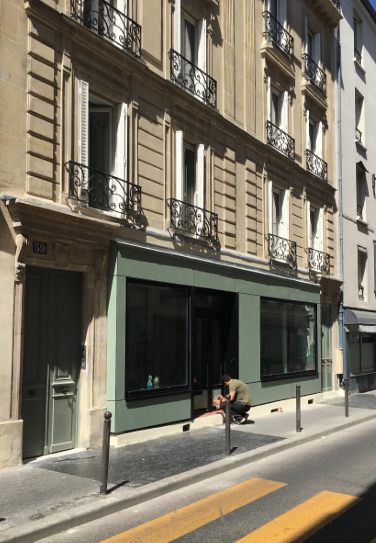 Photo de la devanture verte au rez-de-chaussée du 59 rue Sauffroy avec un homme accroupi devant après la restructuration et réhabilitation de l’immeuble