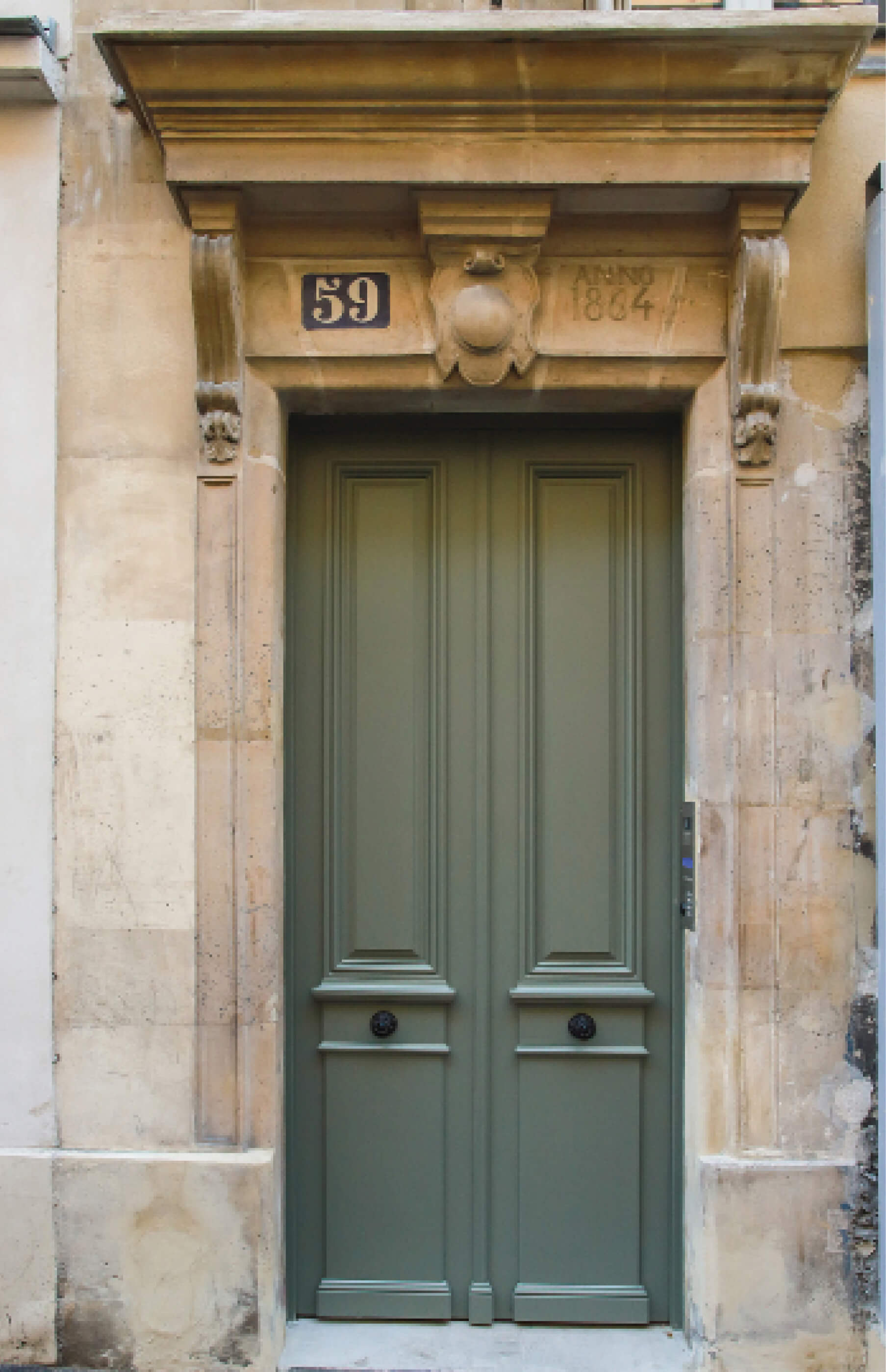Photo de la porte d’entrée verte de l’immeuble entourée des pierres de taille de la façade après restructuration et réhabilitation rue Sauffroy