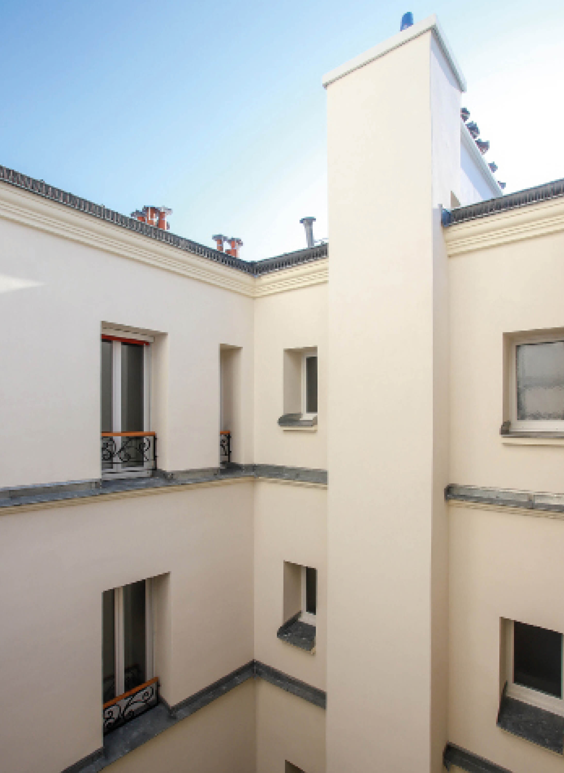 Photo des fenêtres et de la façade des deux derniers étages côté cour avec ciel bleu