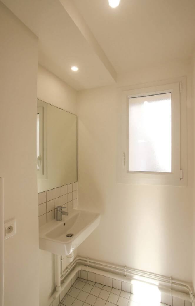 Photo salle de bain blanche avec lavabo et miroir après restructuration et réhabilitation rue Sauffroy
