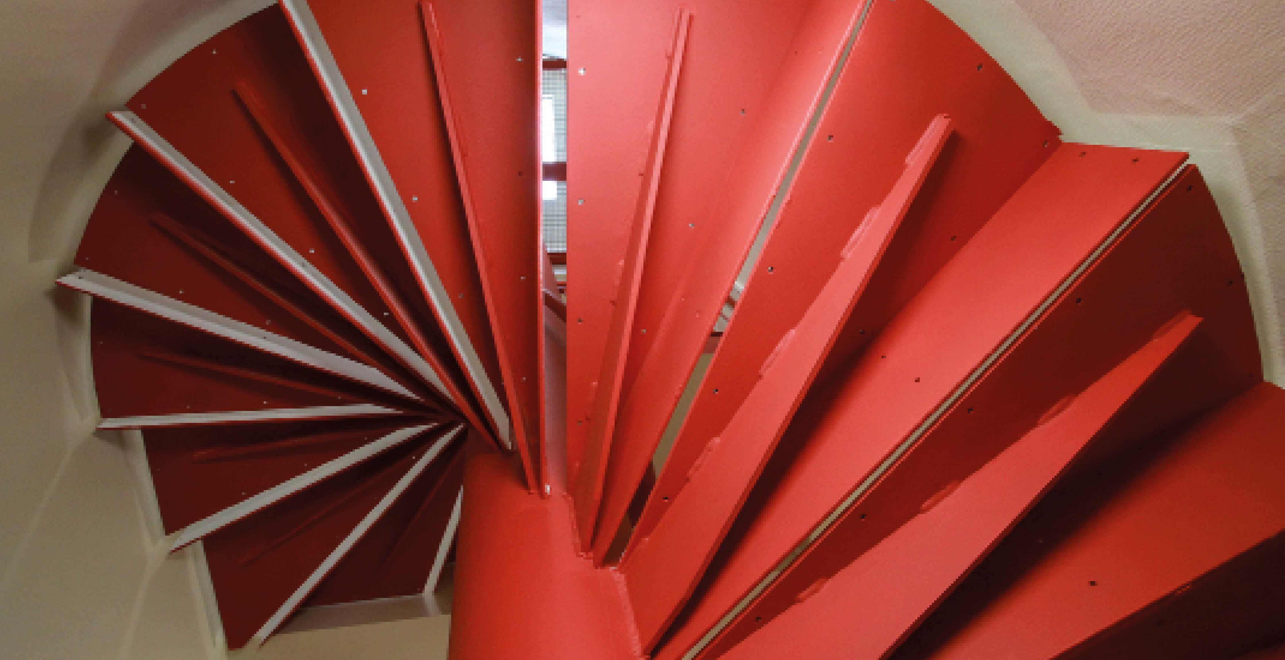 Photo prise sous l’escalier rouge dévoilant la spirale de cet équipement installé pour le projet de restructuration et réhabilitation rue Sauffroy