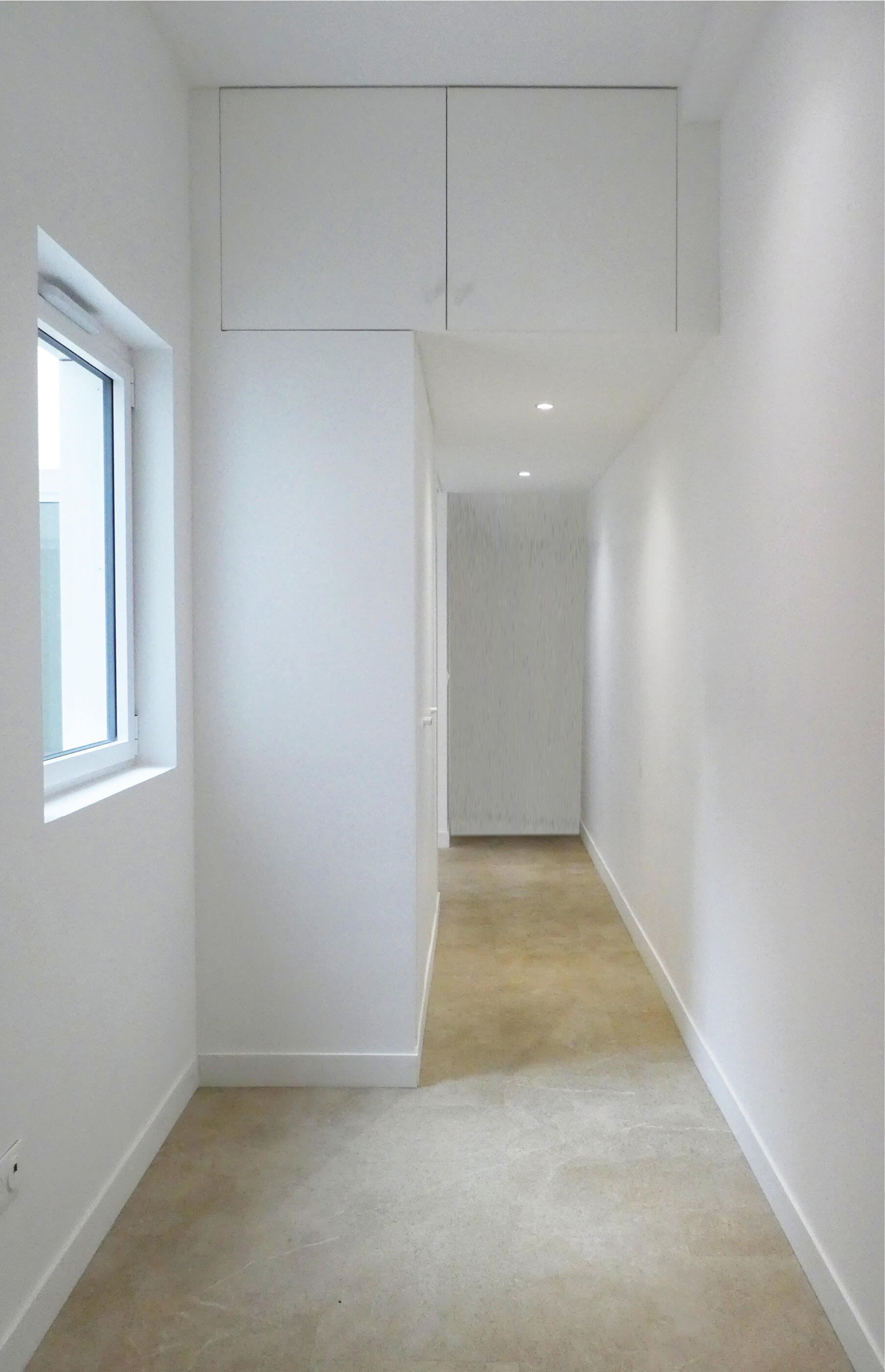 Photo du couloir blanc et lumineux avec placards en hauteur après restructuration et reconversion en logement square Eugène Hatton.