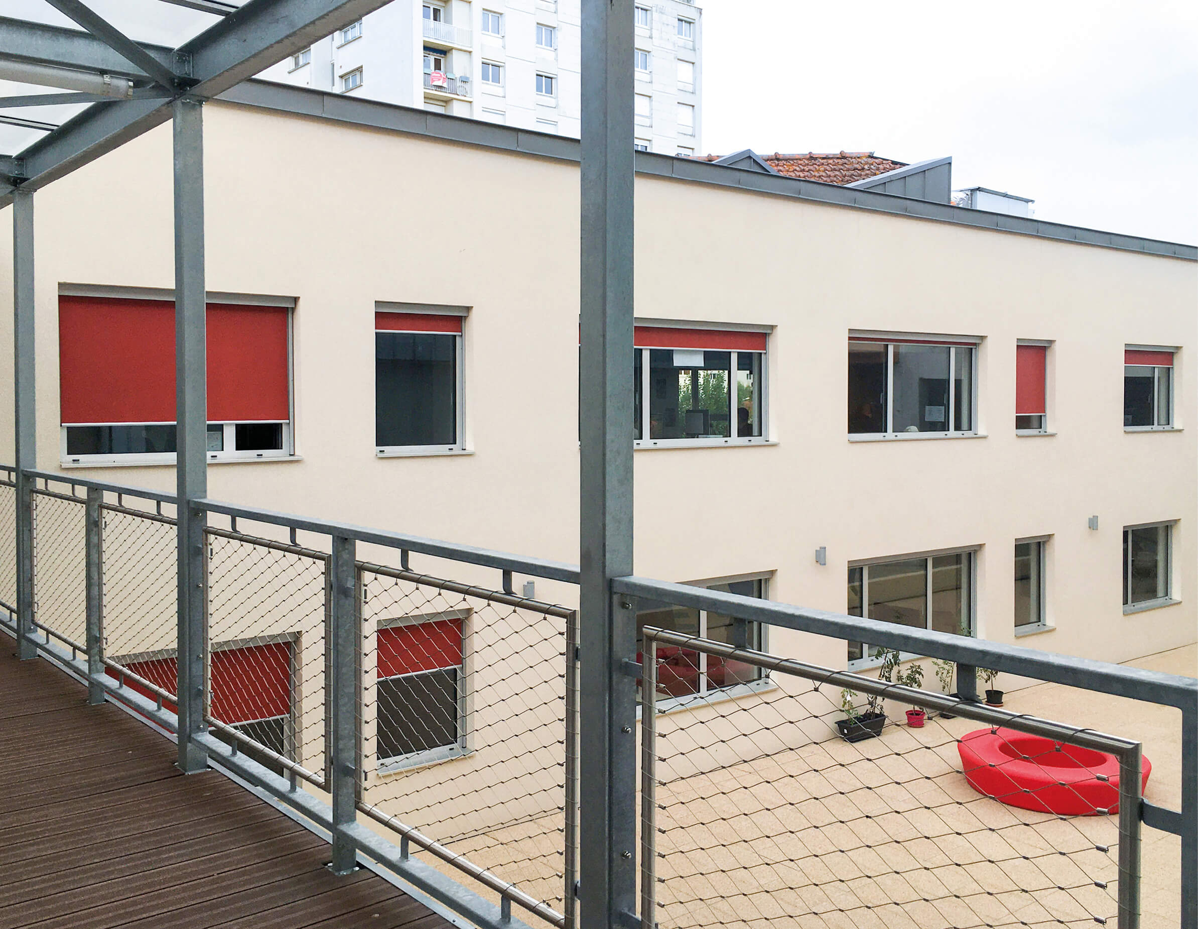 Photo de la cour Timbror prise de la passerelle apres la reconversion en bureaux avec facade aux fenetres equipees de stores rouges