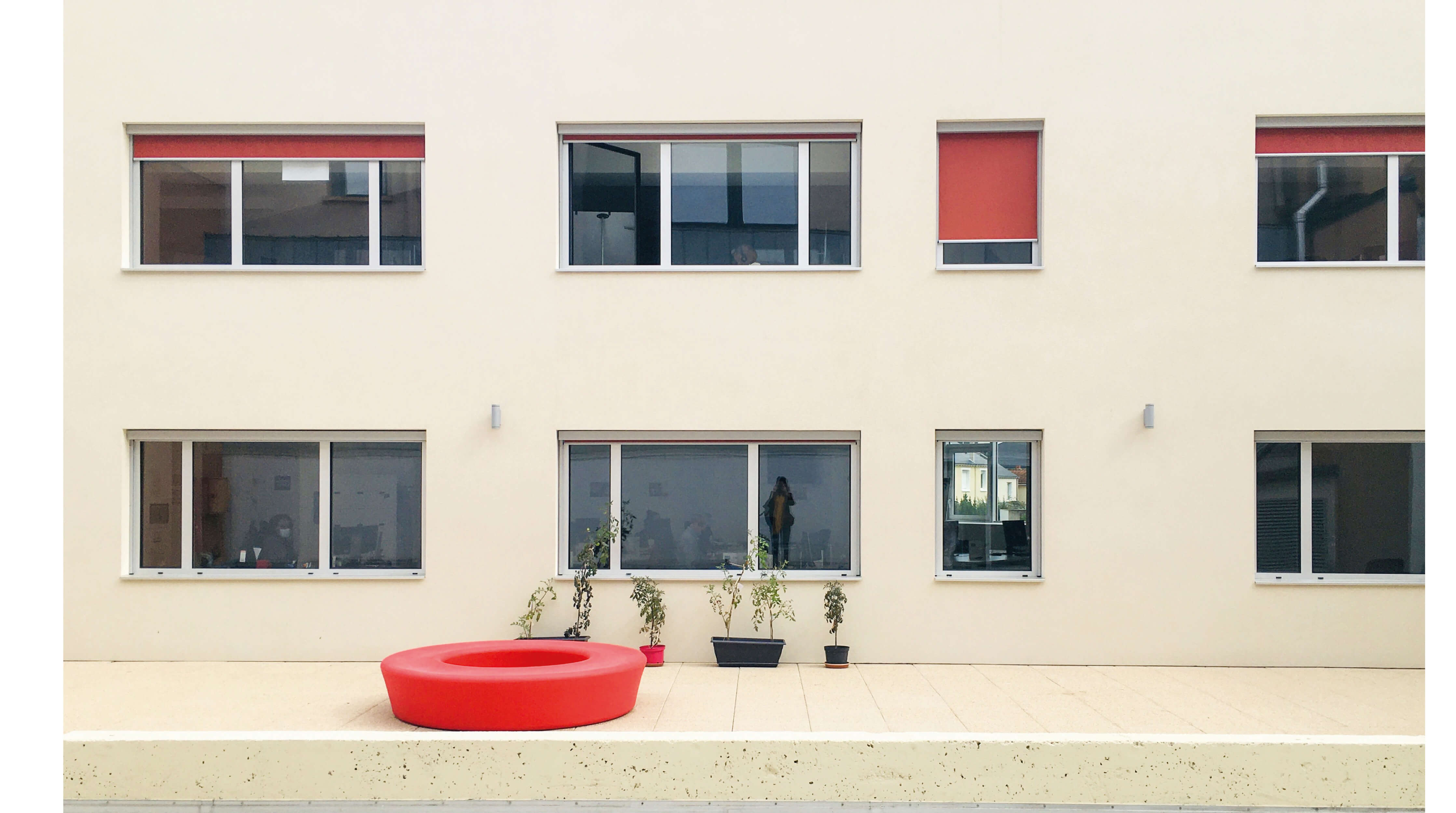 Photo lumineuse de la facade Timbror avec stores rouges cote cour apres la reconversion en bureaux